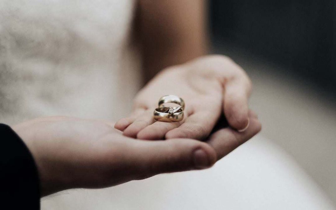 Two hand holding wedding rings